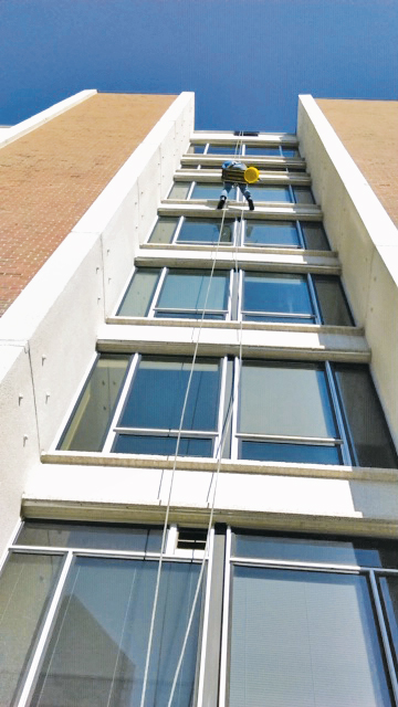 One of Streak-Free Window Cleaning's workers cleaning the windows on a high-rise using special equipment